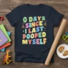 0 Days Since I Last Pooped Myself humorous quote t-shirt with colorful block letters and poop emojis