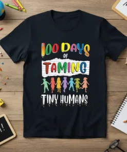 100 Days of Taming Tiny Humans text with colorful letters and children graphic on a black t-shirt