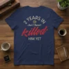 T-shirt with "2 Years In And I Haven't Killed Him Yet" text in cream and red, featuring wedding rings graphic