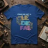 Blue t-shirt with "3 Things God Can't Do LIFE DIE FADE" in colorful, stylized text and a gold shield graphic