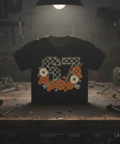 Black t-shirt with large number 67 design featuring checkered pattern, orange and white daisies, and racing flags
