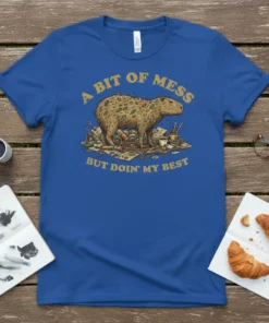A blue t-shirt with the quote "A Bit of Mess But Doin' My Best" and an illustration of a capybara