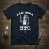A Salt With A Deadly Weapon T-Shirt featuring a cartoon salt shaker holding a knife, wearing sunglasses, with bold white