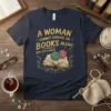 A WOMAN CANNOT SURVIVE ON BOOKS ALONE SHE ALSO NEEDS quote on a navy t-shirt with an open book and