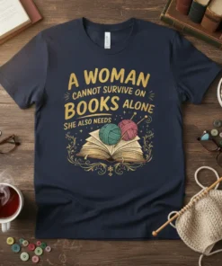 A WOMAN CANNOT SURVIVE ON BOOKS ALONE SHE ALSO NEEDS quote on a navy t-shirt with an open book and