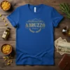 Abruzzo Italia text and wreath graphic on a royal blue t-shirt, representing Italian travel and heritage