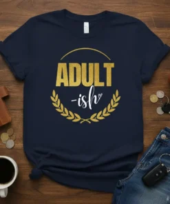 Navy t-shirt with "ADULT-ish" text in gold glitter and white script, framed by a gold laurel wreath