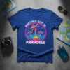 Retro "Another Day In Paradise" text with vibrant palm trees and sunset graphic on a blue t-shirt