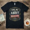 Ask Me About Medicare quote in vintage style typography on a navy blue t-shirt, featuring a caduceus medical symbol