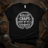 Assless Chaps Made Me Do It text with wings and gear graphic on a black t-shirt