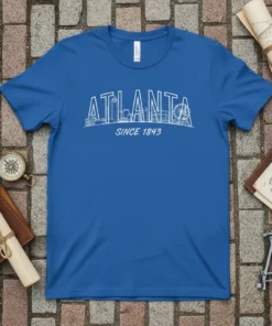 Atlanta skyline graphic with "ATLANTA SINCE 1843" text in white outline on a blue t-shirt