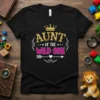 Black t-shirt with "AUNT OF THE WILD ONE" in gold and pink glitter text, topped with a gold crown graphic