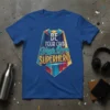 Blue t-shirt with bold text "BE YOUR OWN Your Own SUPERHERO" designed as a superhero cape graphic