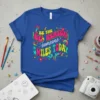 Be the Reason Someone Smiles Today quote in colorful retro font on a blue t-shirt with floral and rainbow graphics