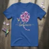 Blue t-shirt with the word "believe" in gold script, a hummingbird, and purple flowers