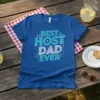 Blue t-shirt with "BEST HOST DAD EVER" in white and aqua lettering, surrounded by small stars and lines