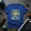 Best Papa In The Galaxy text with astronaut and UFO graphic on a blue t-shirt