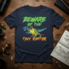 Beware Of The Tiny Raptor t-shirt design with a green conure parrot and dinosaur skeletons, featuring neon green and orange