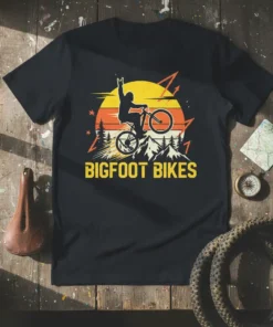 Bigfoot riding a mountain bike with the text Bigfoot Bikes, featuring a retro sunset and mountains