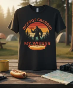 Bigfoot holding a hot dog with text "BIGFOOT GRABBED MY WIENER" on a vintage sunset graphic