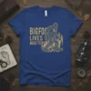 Bigfoot Lives Matter text with a Bigfoot graphic and forest illustration on a blue t-shirt
