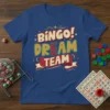 Blue t-shirt with "BINGO! DREAM TEAM" text in colorful, distressed typography. Features stars and ribbons, evoking a fun bingo theme