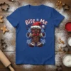 A blue t-shirt featuring the text "Bite Me" above a smiling gingerbread man wearing a Santa hat, with festive stars