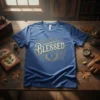 Blue t-shirt with "Blessed" text in gold distressed font, featuring a cross and laurel wreath graphic
