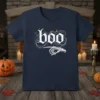 Navy blue t-shirt with white gothic font spelling "boo" and a skeleton hand pointing left, surrounded by wisps and stars