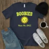 Boobies Make Me SMILE quote with a cheerful sun graphic on a navy t-shirt