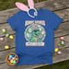 Bunny Saurus T-Shirt with a cartoon T-Rex wearing bunny ears and holding a donut, surrounded by Easter eggs