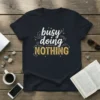 Busy doing NOTHING quote on a black t-shirt with white and gold distressed typography