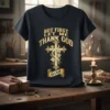 Black t-shirt with gold text "BUT FIRST LET ME THANK GOD" above a decorative cross with grapes and a banner