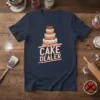 CAKE DEALER text design with a multi-tiered cake graphic, cream and pink frosting, and strawberries on a navy t-shirt