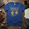 Camino de Santiago t-shirt with hiker graphic, scallop shell, and mountains in gold design