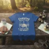 Camping without beer is just sitting = the woods quote on a blue t-shirt featuring a tent graphic under a
