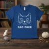 White line art of a cat's face with "CAT • FACE" text below, printed on a royal blue t-shirt