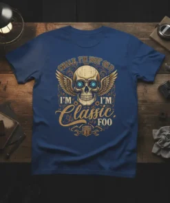 T-shirt with text "CHALE, I'M NOT OLD I'M I'M CLASSIC FOO" featuring a winged skull graphic and piston design