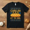 Black t-shirt with "Challah At Ya Girl" text, a braided challah loaf graphic, dreidels, and Star of David symbols for