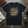 Dark t-shirt with "CHAOS FOLLOWS ME" text in a distressed, decorative font, surrounded by steampunk-inspired gears and leopard print accents