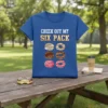 Blue t-shirt with "Check Out My Six Pack" text above six colorful donuts graphic