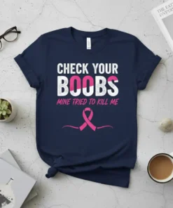 Navy blue t-shirt with white and pink text reading "CHECK YOUR BOOBS MINE TRIED TO KILL ME" and a pink