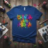 Chinga La Migra text in colorful graffiti style on a blue t-shirt, with spray paint splatters