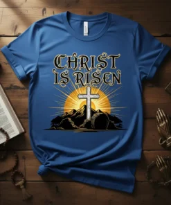 Christ Is Risen t-shirt with a white cross, mountains, and sunrise graphic. Religious Easter apparel