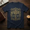 Navy t-shirt with ornate gold design featuring the text "Christ Jesus Lord Savior King" and a cross graphic