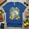 Blue t-shirt with "Ciao bella" text, surrounded by lemons and flowers, depicting an Italian coastal town scene