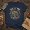 Circe's BBQ Prize Winning Pulled Pork T-Shirt featuring a pig on a grill, "Circe's BBQ Est. 700 BC", and "Prize