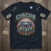 CIRCUS STAFF text on a navy t-shirt with a graphic of a colorful circus tent and decorative elements, suggesting carnival