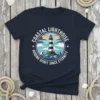 Coastal Lighthouse Guiding Spirit Since Eternity t-shirt design with a black and white lighthouse on a rocky island surrounded by