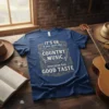 T-shirt design with text "IT'S OK if you don't like COUNTRY MUSIC everyone has GOOD TASTE" in ornate gold lettering